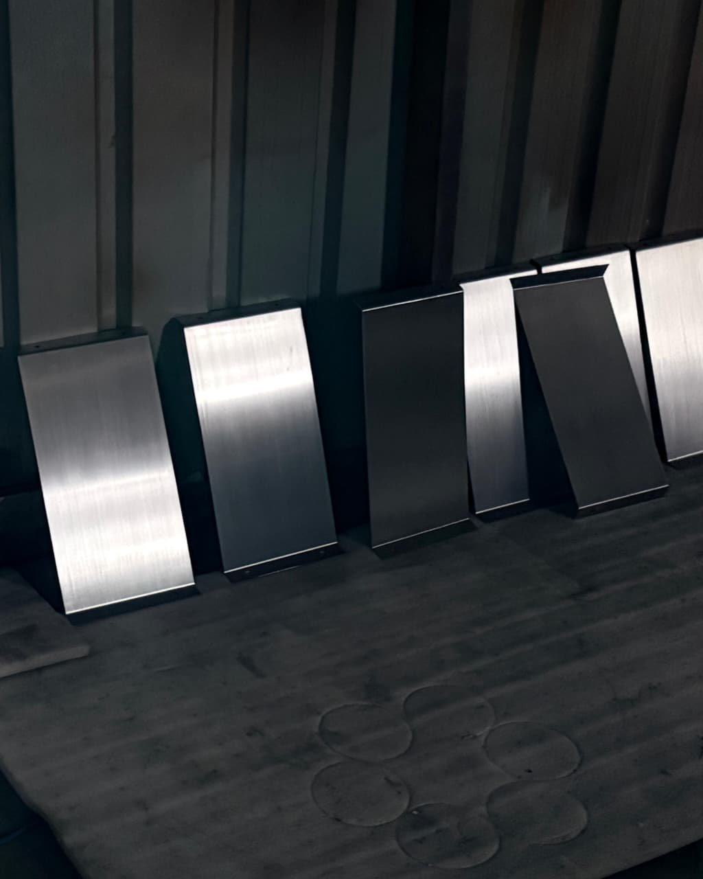 Handcrafted brushed stainless steel furniture legs lined up in Metal Shades workshop, showcasing bespoke metalwork craftsmanship