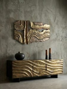Modern luxury living room featuring a monolithic antique brass credenza with 3D fluid wave patterns, paired with a matching abstract burnt copper metal wall art installation against a raw concrete texture wall.