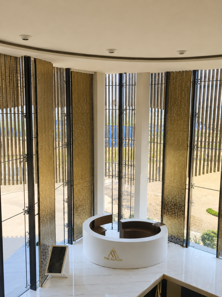 Luxury hotel lobby featuring bespoke brass perforated metal screens with a curved reception desk, custom fabricated by Metal Shades.
