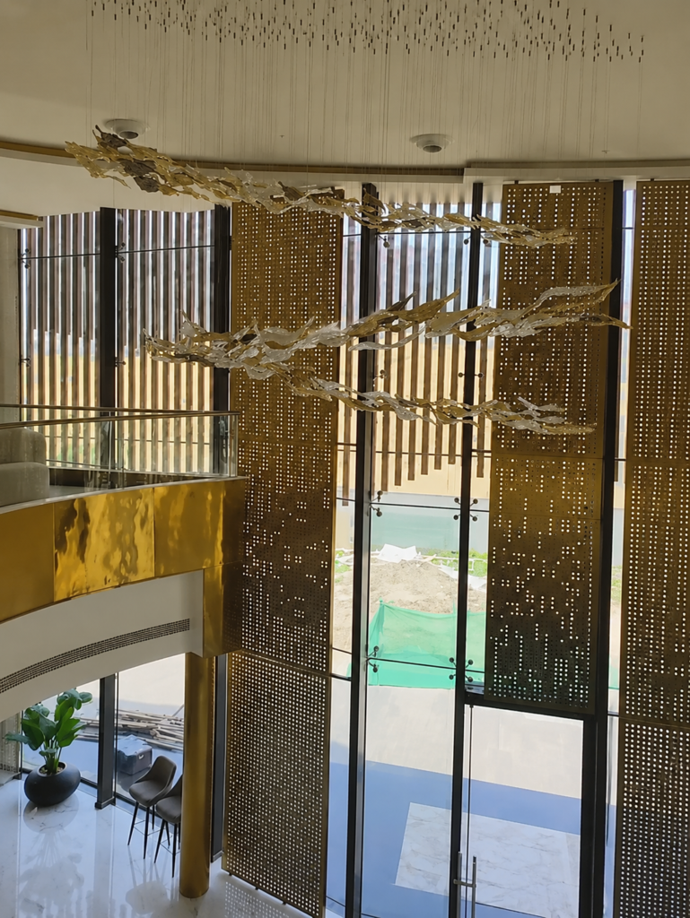 Luxury double-height lobby featuring bespoke perforated metal screens with a sculptural suspended metal installation by Metal Shades.