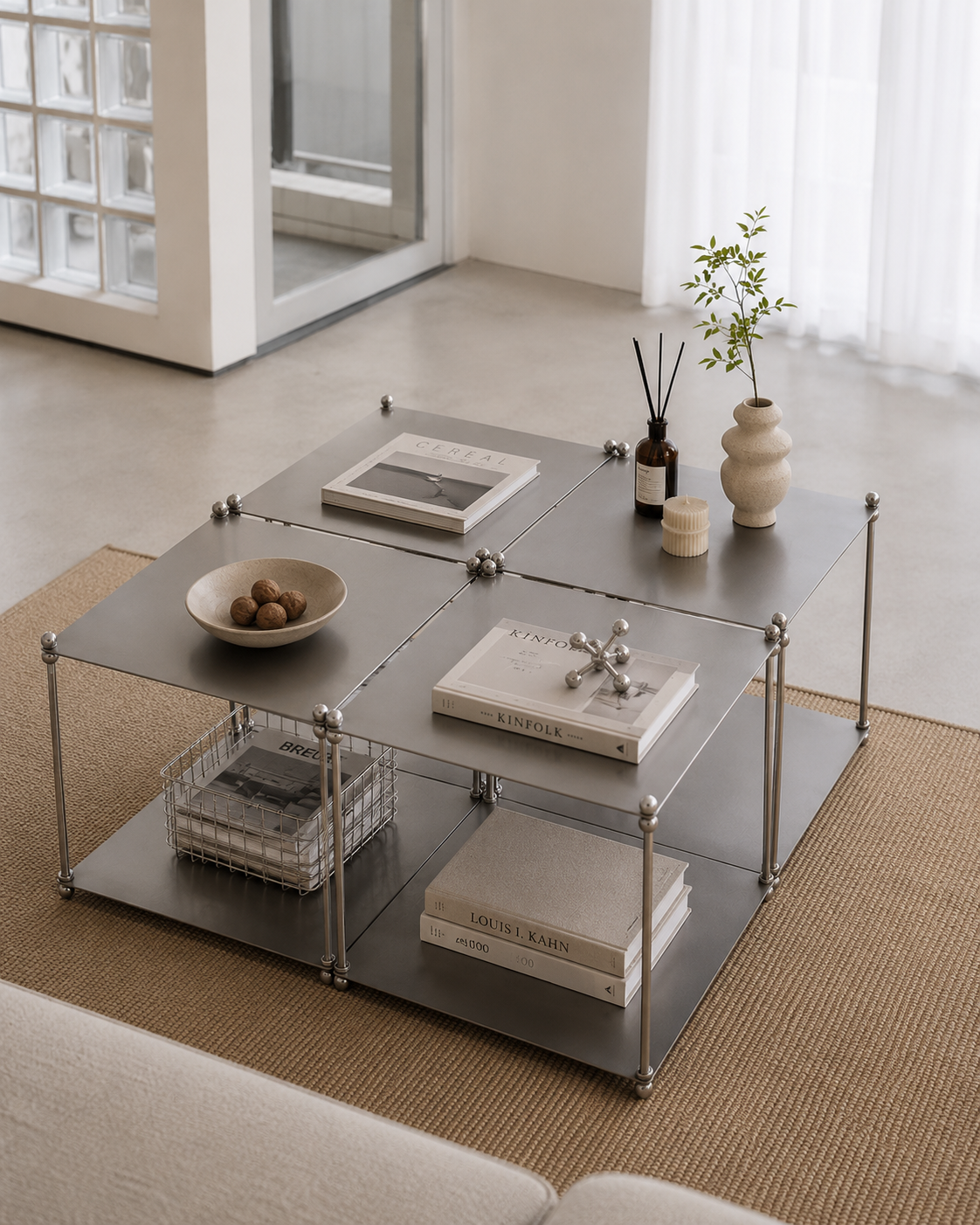 Modular Metal Coffee Table with Ball-Joint Frame and Open Shelf Overhead view of a gunmetal modular coffee table with four connecting tabletop panels, ball-joint legs, and an open lower shelf styled with books and decor