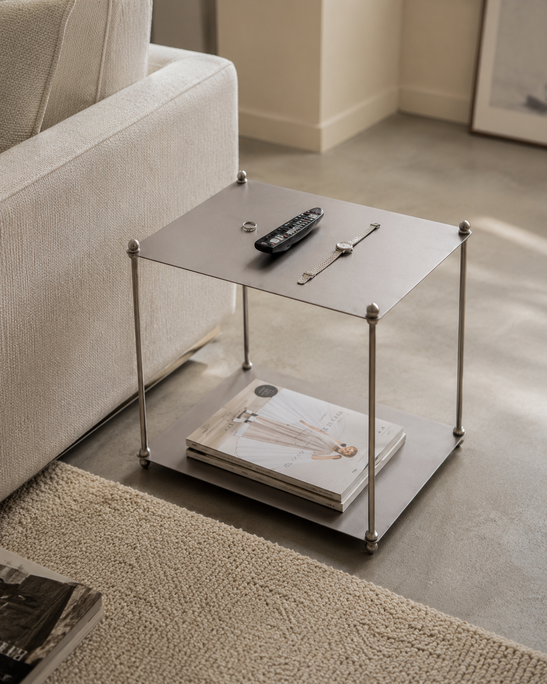 Minimalist Metal Side Table with Lower Storage Shelf Small gunmetal side table with silver ball-joint legs beside a beige sofa, topped with a remote control, watch, and ring, with magazines stored on the lower shelf